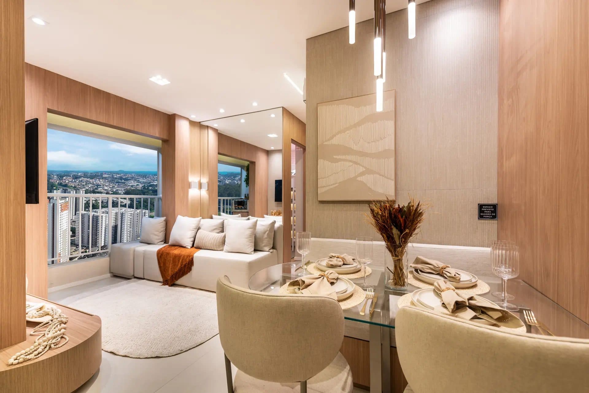 Sala de estar e jantar integrada com mesa de vidro, cadeiras estofadas, sofá e vista para a cidade