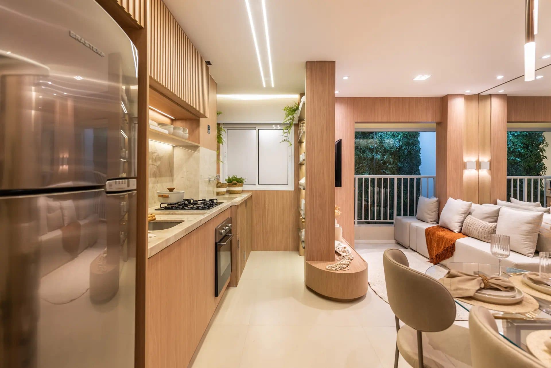 Cozinha planejada com armários amadeirados, eletrodomésticos embutidos e integração com a sala